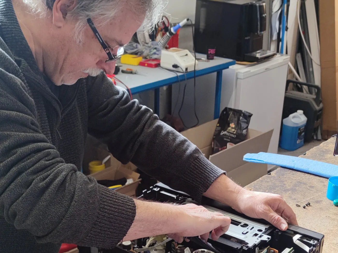 Les réparateurs d'ASD Electronique manipulant un écran de téléviseur dans l'atelier de Perpignan